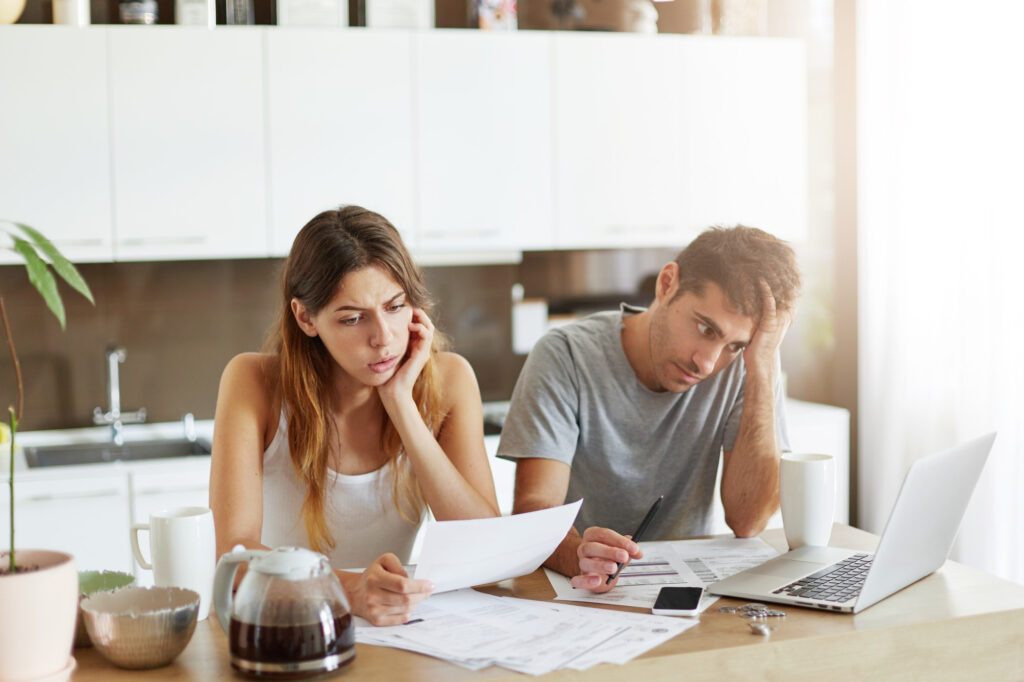 Stressed couple reviewing bills at home before calling a bankruptcy lawyer in Anniston AL