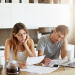 Stressed couple reviewing bills at home before calling a bankruptcy lawyer in Anniston AL
