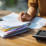 Person organizing bills and paperwork while learning about Chapter 7 bankruptcy qualifications